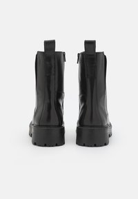 Černé kožené kotníkové boty s hladkým povrchem, robustní podrážkou, zadním poutkem a bočním zipem. Minimalistický design bez ozdob.