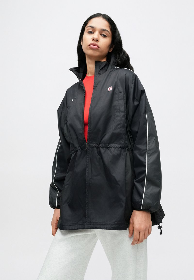 Schwarze Nylon-Windjacke mit durchgehendem Reißverschluss, elastischem Bund und weißen Akzenten. Verfügt über ein dezentes Logo und ein hohes Kragensdesign.