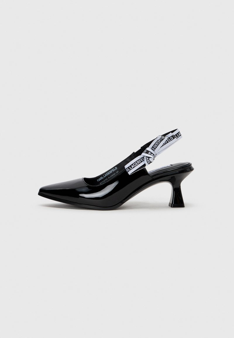 Chaussure slingback en cuir verni noir avec un bout pointu, un talon kitten et une sangle blanche marquée. Texture lisse avec une finition brillante.