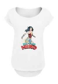 White short-sleeve t-shirt featuring a graphic of a female character in a red and gold outfit, with "BE THE HERO" text in bold colors.
