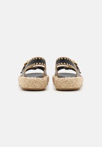 Svarta espadrillosandaler med två breda remmar, vävd jutesula och zigzagstygn på remmarna. Platt design med öppen baksida.