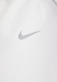 Ropa blanca de Nike con un sutil logo gris. La tela tiene una textura acanalada, ofreciendo una apariencia deportiva y funcional.