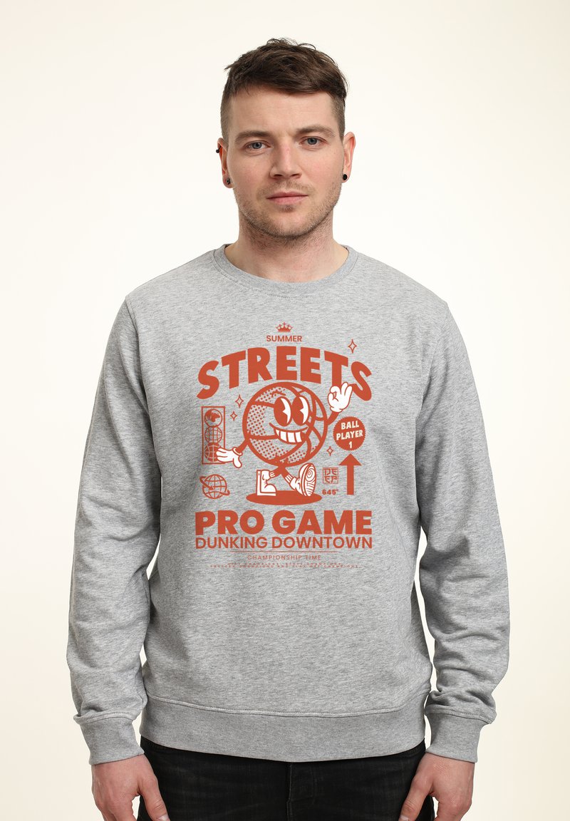 Šedá mikina s oranžovou grafikou s karikaturním basketbalem, textem "STREETS PRO GAME DUNKING DOWNTOWN" a žebrovanými manžetami.