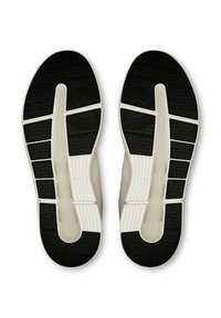 Vita och svarta atletiska skosulor med texturerade mönster och flexibla spår för grepp, utformade med en modern och strömlinjeformad design.