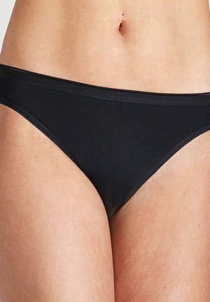 Weiblicher Oberkörper in schlichter schwarzer Baumwoll-Bikiniunterwäsche, die den unteren Bauch und die Oberschenkel zeigt.