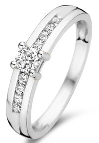 Bague en argent avec un diamant rond central, flanqué de petits diamants le long d'un bandeau poli avec une finition lisse et élégante.