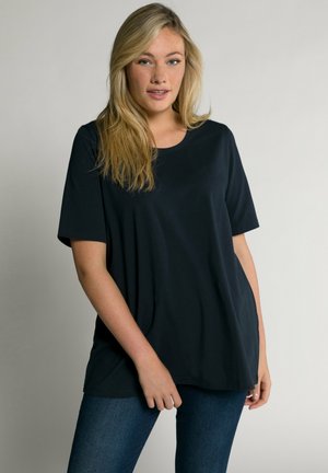 T-shirt nera a maniche corte con scollo rotondo, vestibilità comoda e tessuto morbido; abbinata a jeans blu scuro in una posa casual.