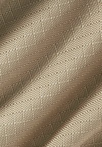 Tela texturizada beige con un patrón tejido, que presenta un brillo sutil y diferentes tonos de beige que crean una apariencia ondulada.