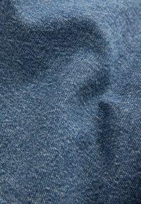 Heledas sinise teksariide lähivaade, mis näitab kootud tekstuuri ja kergeid kortse.