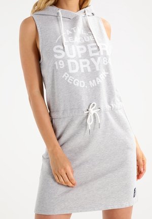 Grijze mouwloze jurk met capuchon, trekkoord in de taille en grote witte opdruk met de tekst "SUPERDRY" en "ATHL. LEAGUE 1984." Van katoen.