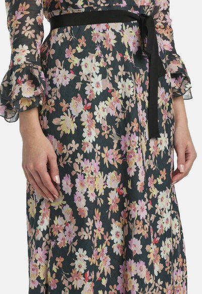 Robe noire à fleurs avec des fleurs roses, blanches et jaunes, manches transparentes à volants, et un nœud de ceinture noir à la taille.