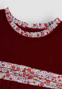 Vestido burdeos con un cuello y cinturilla estampados con flores. Detalle de escote con volantes, textura suave y forma estructurada.