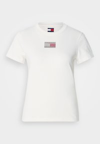 Hvid bomulds t-shirt med et lille grafisk rektangel med et rødt, hvidt og blåt design. Korte ærmer og rund hals.