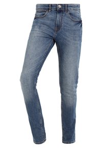 Jeans ajustados en denim azul medio con un sutil desgaste, diseño de cinco bolsillos, cierre frontal con botón y pasadores para cinturón.