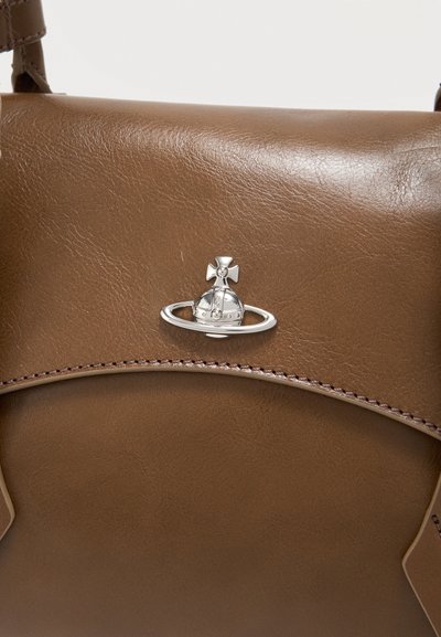 Καφέ δερμάτινη τσάντα χειρός με ασημένιο λογότυπο σφαίρας και σταυρού στο κέντρο της μπροστινής πτέρυγας, με λεπτομερείς ραφές κατά μήκος της άκρης.