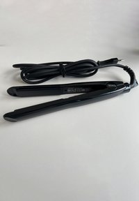 Zwarte Wahl haar stijltang met een netjes opgerold netsnoer, geplaatst op een witte ondergrond.