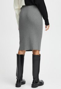 Gray ribbed knit skirt that falls below the knee, paired with knee-high black leather boots featuring a side zipper and textured surface.