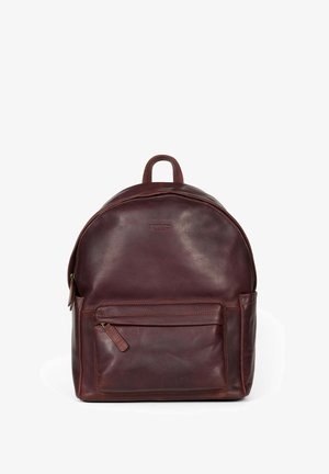 Mochila de cuero marrón con forma redondeada, bolsillo frontal con cremallera y asa en la parte superior; textura suave con un sutil detalle de marca en la parte delantera.