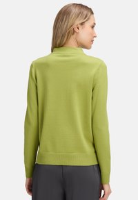 Zöld pulóver kerek nyakkal, bordás mandzsetta és szegély. Sima textúra és testhezálló kialakítás, hátulról bemutatva, látható logók nélkül.