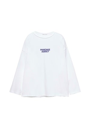 Bela majica z dolgimi rokavi in okroglim izrezom ter temno modrim napisom "PANCAKE ADDICT" na sredini sprednje strani.