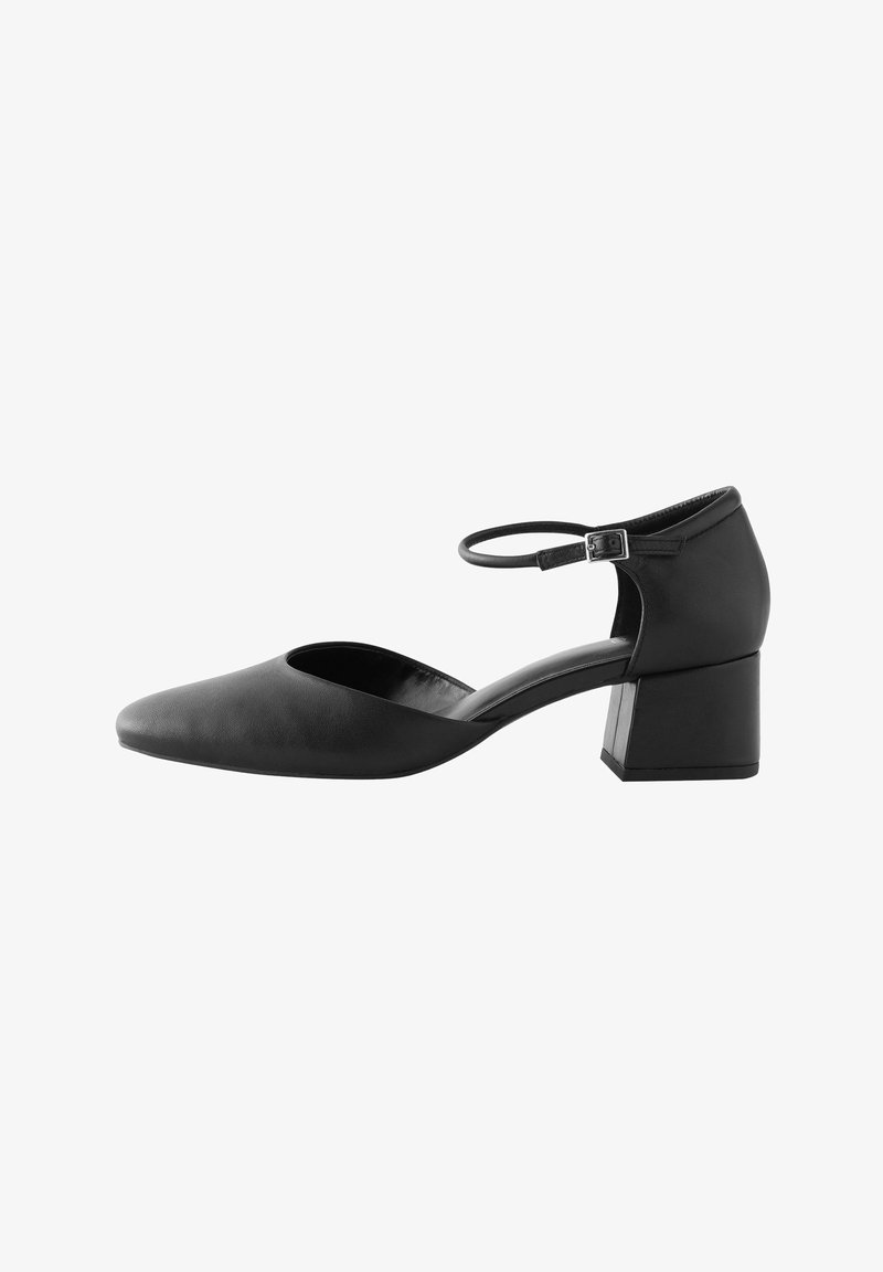 Černé lodičky s ankle strap, špičatou špičkou, nízkým stohovaným podpatkem a hladkou koženou texturou. Obsahují výřezový design po stranách.