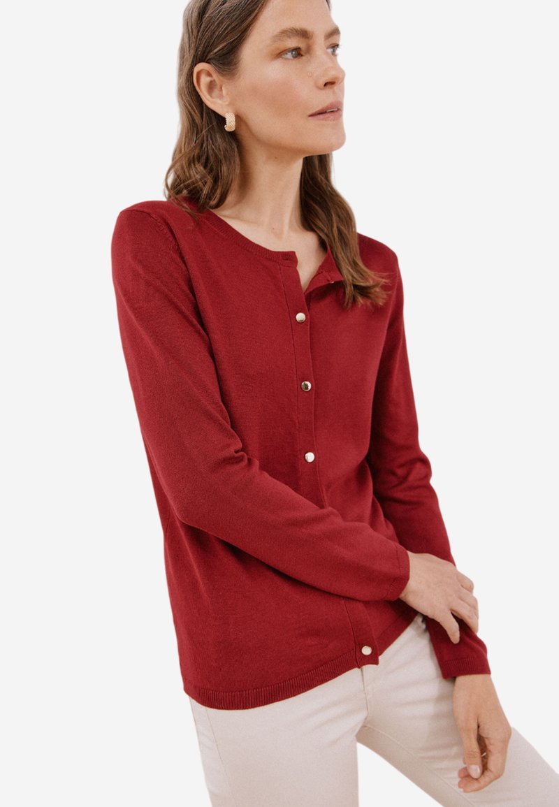 Maglione rosso realizzato in tessuto lavorato a maglia, con collo rotondo, maniche lunghe e chiusura con bottoni sul davanti, dal tocco morbido.