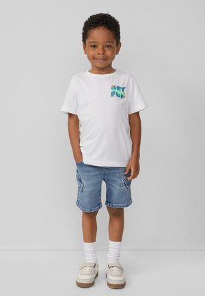 Weißes T-Shirt mit kurzen Ärmeln und buntem "Get Fun"-Grafik auf der Brust, kombiniert mit blauen Jeansshorts und weißen Socken zu Schuhen.