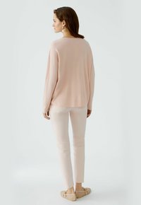 Light pink oversized knit sweater with long sleeves paired with fitted light pink pants. Finished with light beige slip-on shoes.