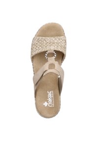 Sandale beige avec une lanière en paille tissée, une semelle intérieure douce et un accent circulaire orné de strass. Design plat et ouvert à l'avant.