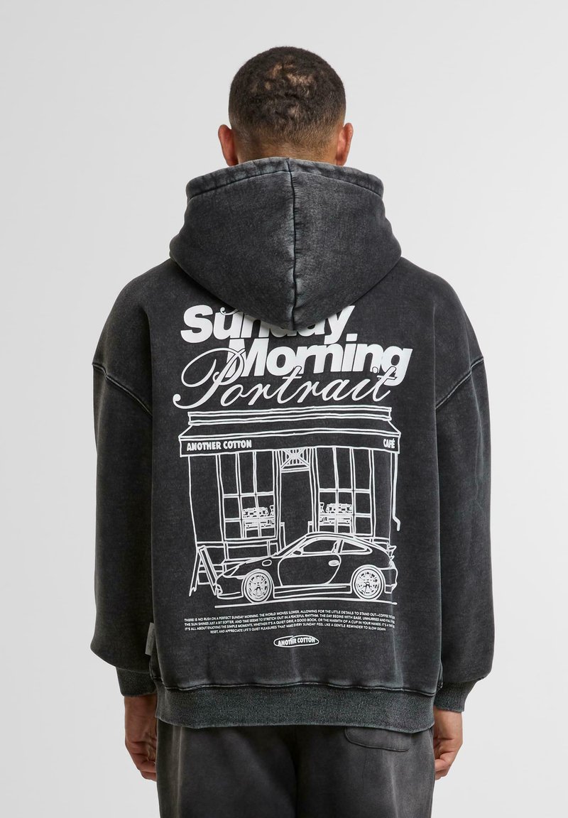 Sweatshirt negru supradimensionat cu glugă, având un imprimeu grafic alb al unei cafenele și al unei mașini pe spate; confecționat dintr-un material de bumbac moale.