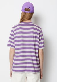 Purple and gray striped t-shirt with a round neckline and short sleeves, featuring a logo on the back of a matching purple cap.