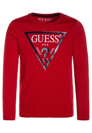 Chemise rouge à manches longues avec un grand logo triangulaire noir portant la mention "GUESS U.S.A. Washed Jeans" et un point d'interrogation au centre.