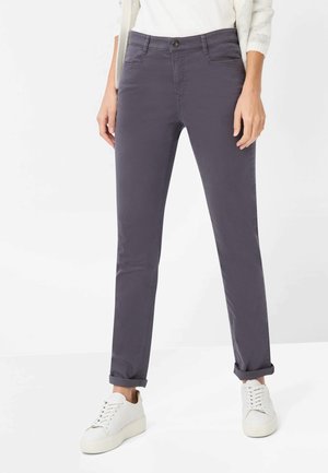 Lilla bomuldsbukser med lige ben, forsynet med forlommer, knaplukning og opsmøgede manchetter, stylet med hvide sneakers.