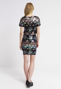 Černé šaty s krátkým rukávem pokryté flitry, s multicolor geometrickými vzory, mají přiléhavý střih a zadní zip.