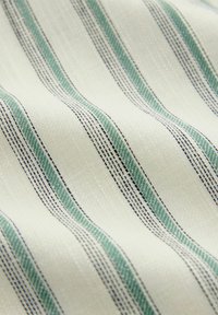Tejido con franjas alternas verdes y negras sobre un fondo crema, con una apariencia texturizada y tejida.