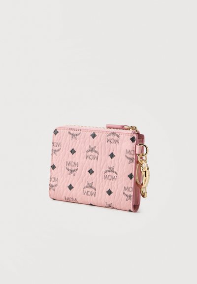 Ροζ πορτοφόλι καρτών από δερματίνη με υφή, με μαύρα λογότυπα MCM και διαμαντένια σχέδια, χρυσλό φερμουάρ, και κρίκο κλειδιών προσαρτημένο στο πλάι.