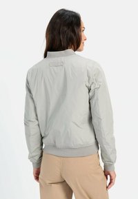 Lys gr�å bomberjakke med ribbede manchetter og kant, der har en glat tekstur og et minimalistisk design. Bagview viser et mærke på halsen.