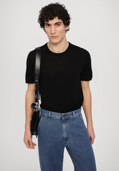 Black short-sleeve t-shirt made of lightweight fabric, paired with light blue high-waisted denim jeans. A black shoulder bag with a strap.