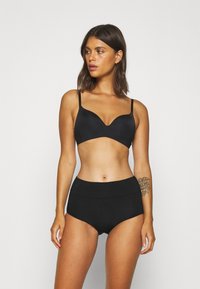 Soutien-gorge noir à décolleté plongeant et bretelles ajustables, associé à une culotte noire taille haute. Texture lisse, design sans couture.
