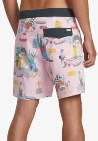 Pantalones de baño rosas con un estampado gráfico colorido que presenta varias ilustraciones, una cinturilla negra y un bolsillo trasero con cierre de botón.