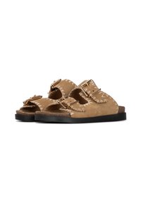 Bruine suede sliders hebben een dubbelband ontwerp met gouden hardwareaccenten. Decoratieve witte stiksels omlijsten de banden en de voetbed.