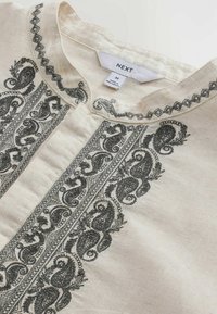 Chemise en tissu crème avec une broderie cachemire noire complexe le long du col et de la patte de boutonnage, taille moyenne indiquée, fabriquée au Bangladesh.