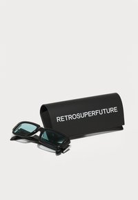 Gafas de sol negras con lentes turquesa, con un marco rectangular grueso, junto a un estuche rígido negro con texto blanco que dice "RETROSUPERFUTURE."