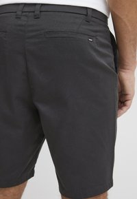 Sorte shorts lavet af et glat stof, med en lige pasform, to baglommer og et lille mærke nær den højre lomme.