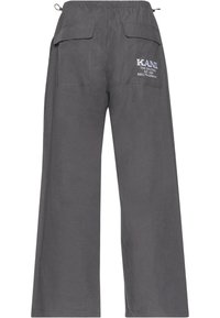 Pantalon large gris foncé avec ceinture élastique, poches à rabat à l'arrière et texte logo blanc "KANI" sur la poche droite.