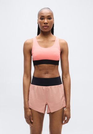 Sutien sport roz cu bandă neagră și pantaloni scurți roz asortați cu talie neagră, confecționați din material ușor și respirabil.