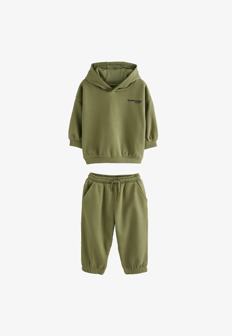Felpa con cappuccio di colore verde oliva, a maniche corte e con testo stampato, abbinata a pantaloni jogging coordinati con vita e polsini elasticizzati.