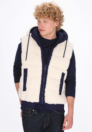 Fleece-Weste in Creme mit navy Akzenten. Verfügt über einen Reißverschluss vorne, zwei Seitentaschen und einen Kordelzugsaum. Die Kapuzendesign sorgt für zusätzliche Wärme.