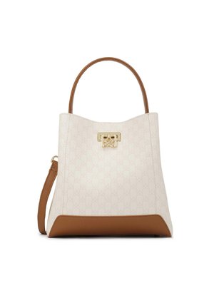 Sac fourre-tout blanc à motif avec une base et des accents en cuir marron. Présente une fermeture en métal doré et deux poignées supérieures.