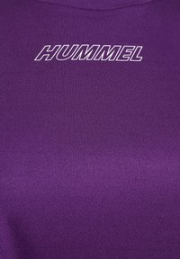 Lila kortärmad skjorta med en strukturerad tyg och en slätstickad rund halsringning, med "HUMMEL"-logotypen i vit text på bröstet.